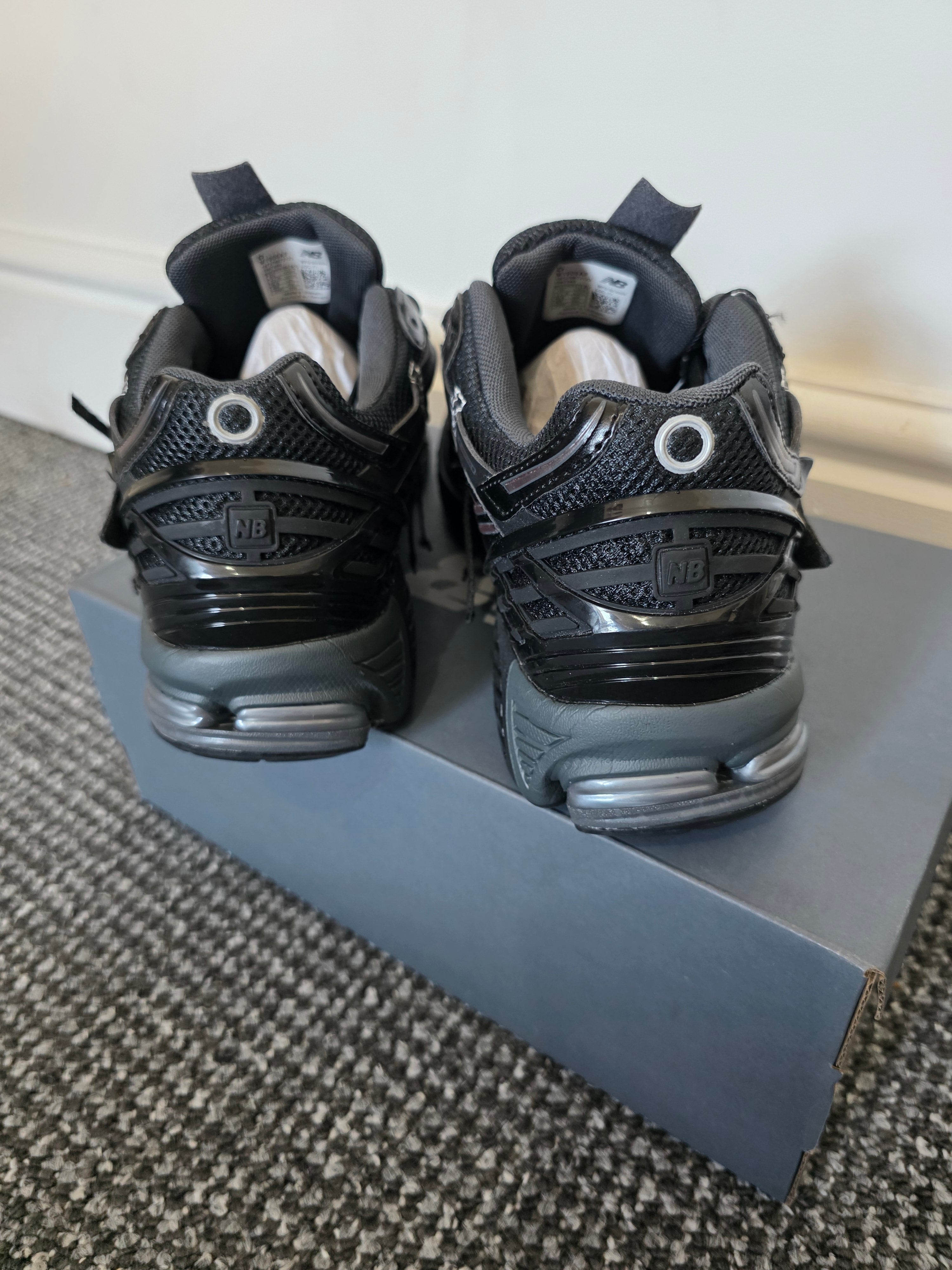 Back view of stylish black sneakers showcasing layered upper design and aggressive look.