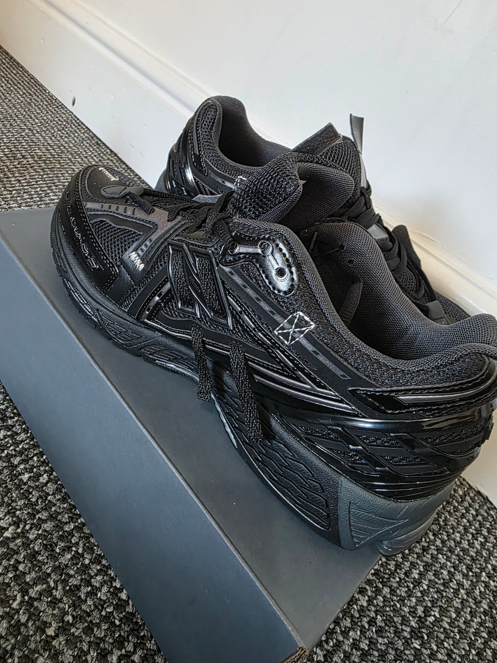 Stylish black sneakers showcased on a box, featuring a modern design and ready for running or casual wear.