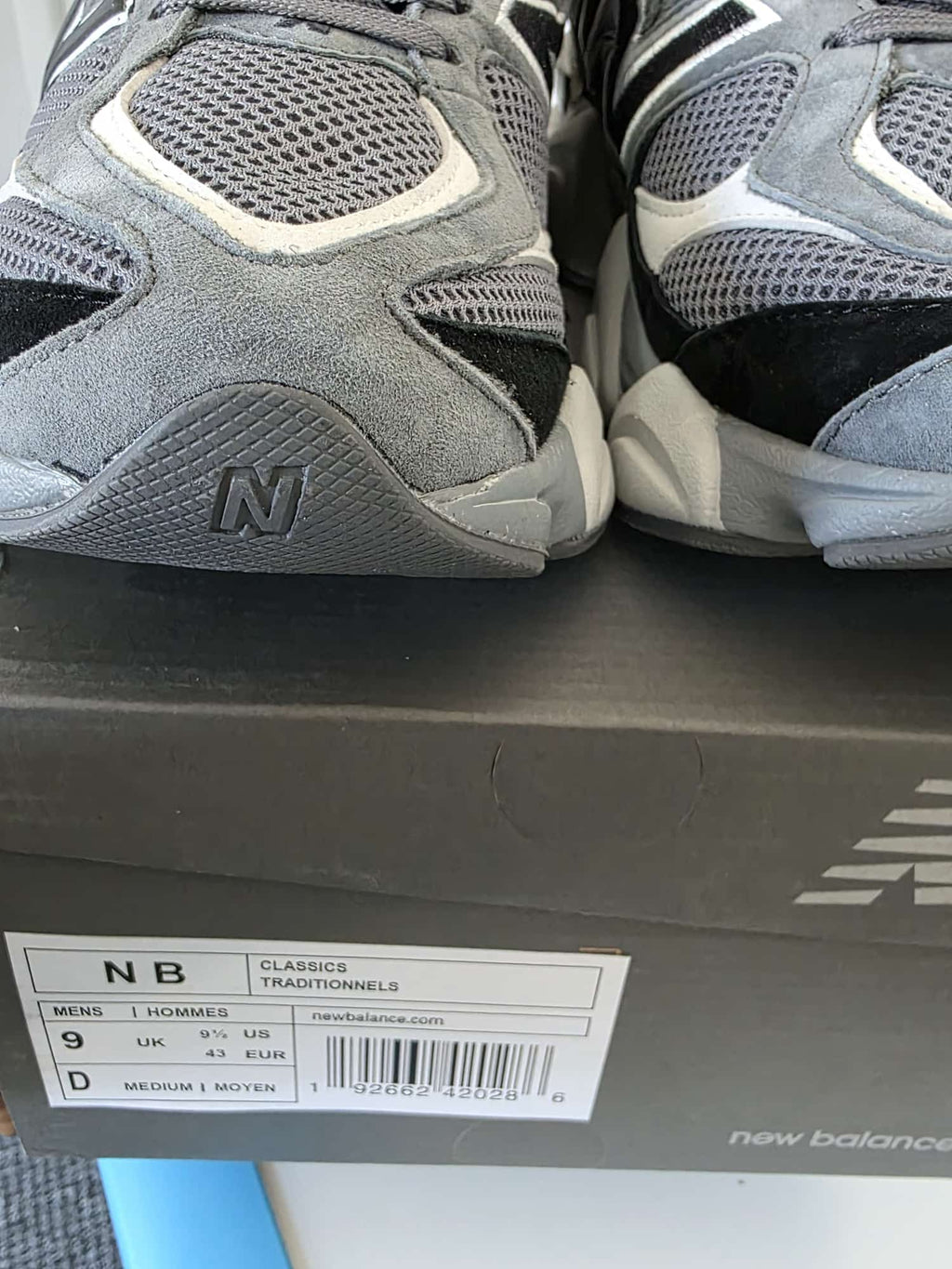 New Balance 9060s gray running shoes displayed on the box with size information.
