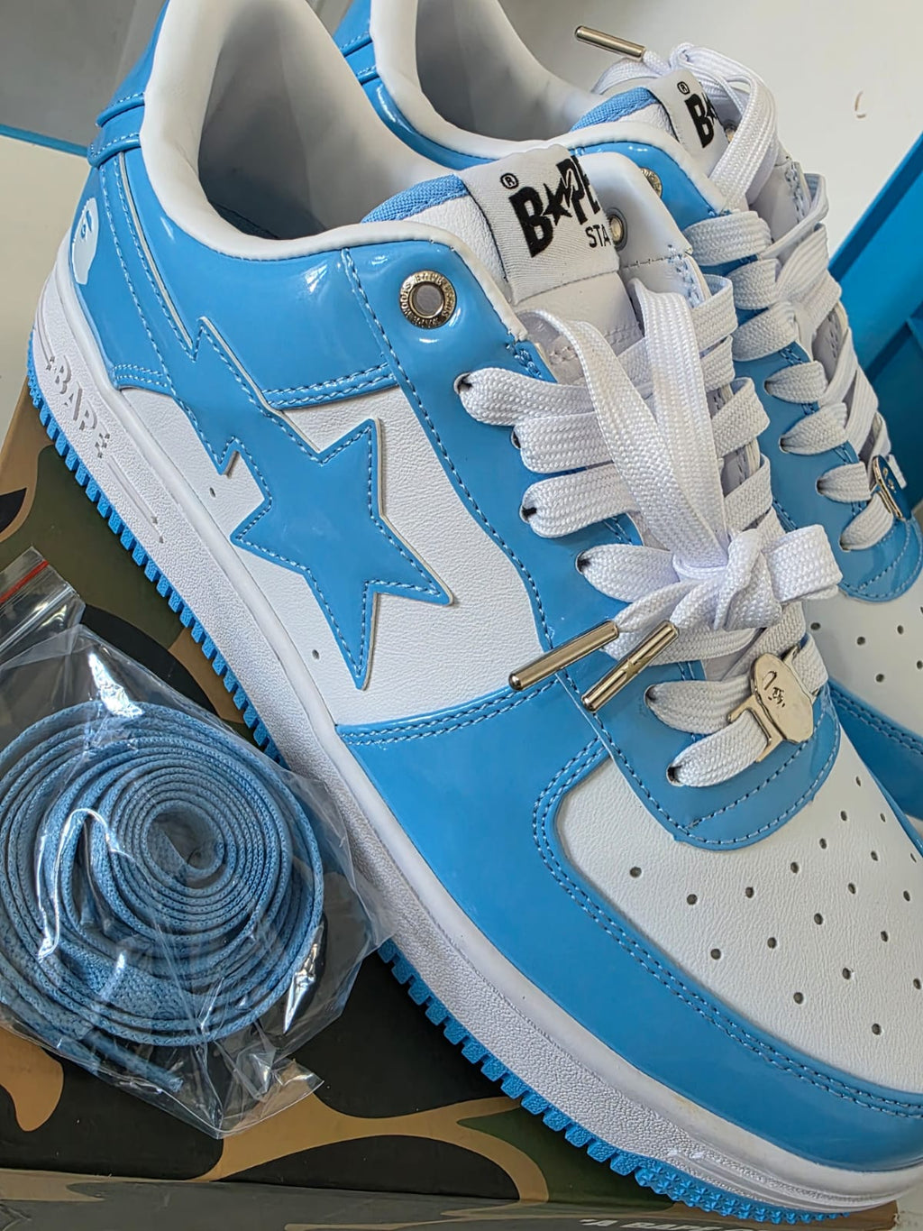 BAPE STA Lows Premium Streetwear Sneakers in blue and white with extra laces laid out.