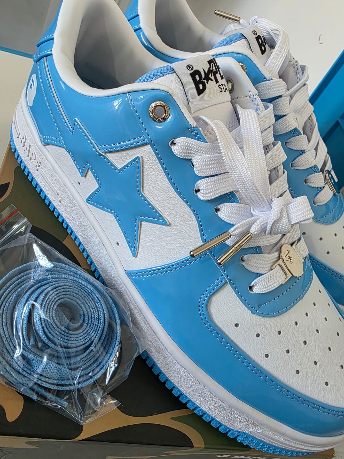 BAPE STA Lows Premium Streetwear Sneakers in blue and white with extra laces laid out.
