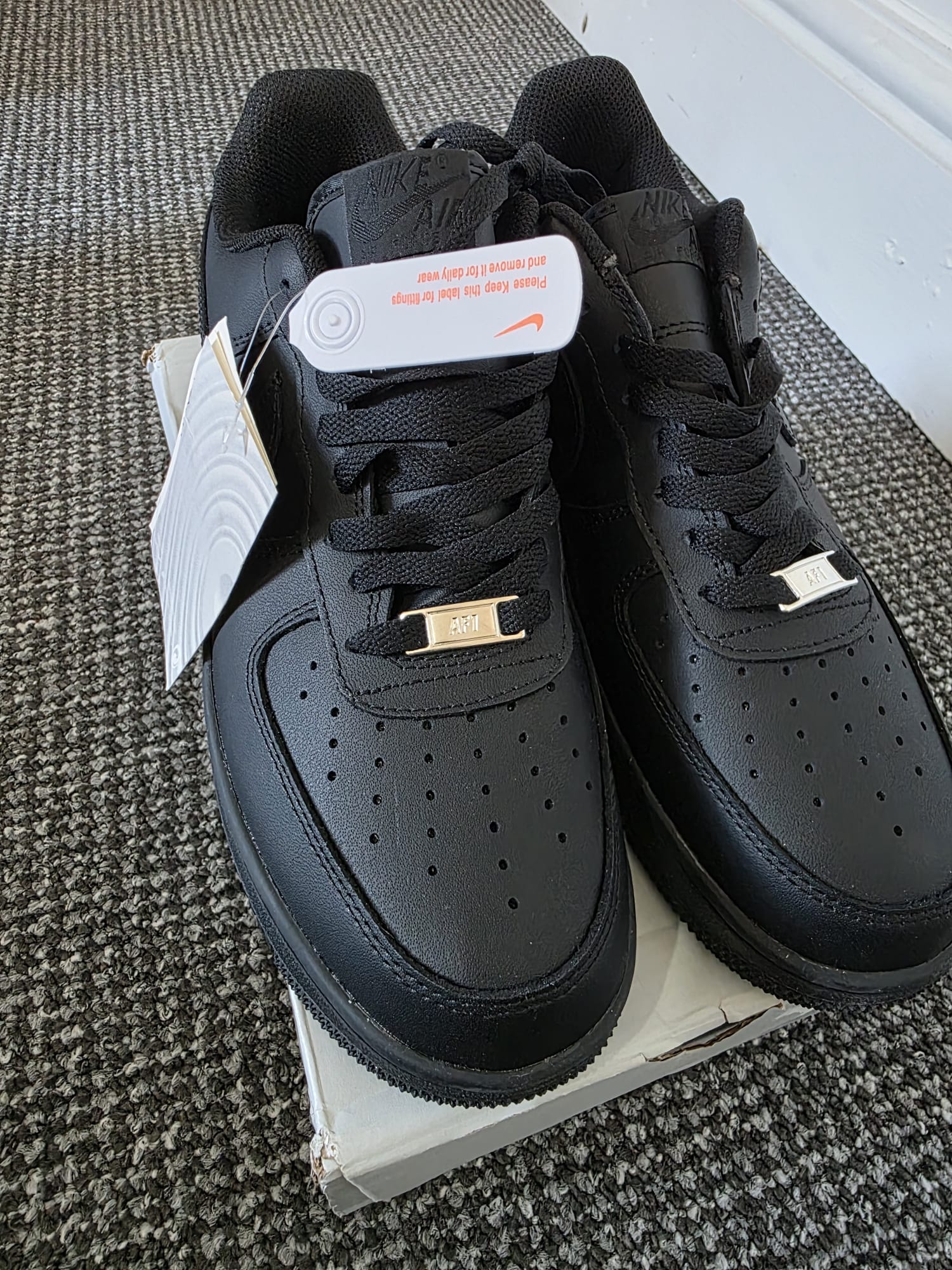 Triple-black Nike Air Force 1 Lows featuring matte black leather, matching laces, and sleek design.