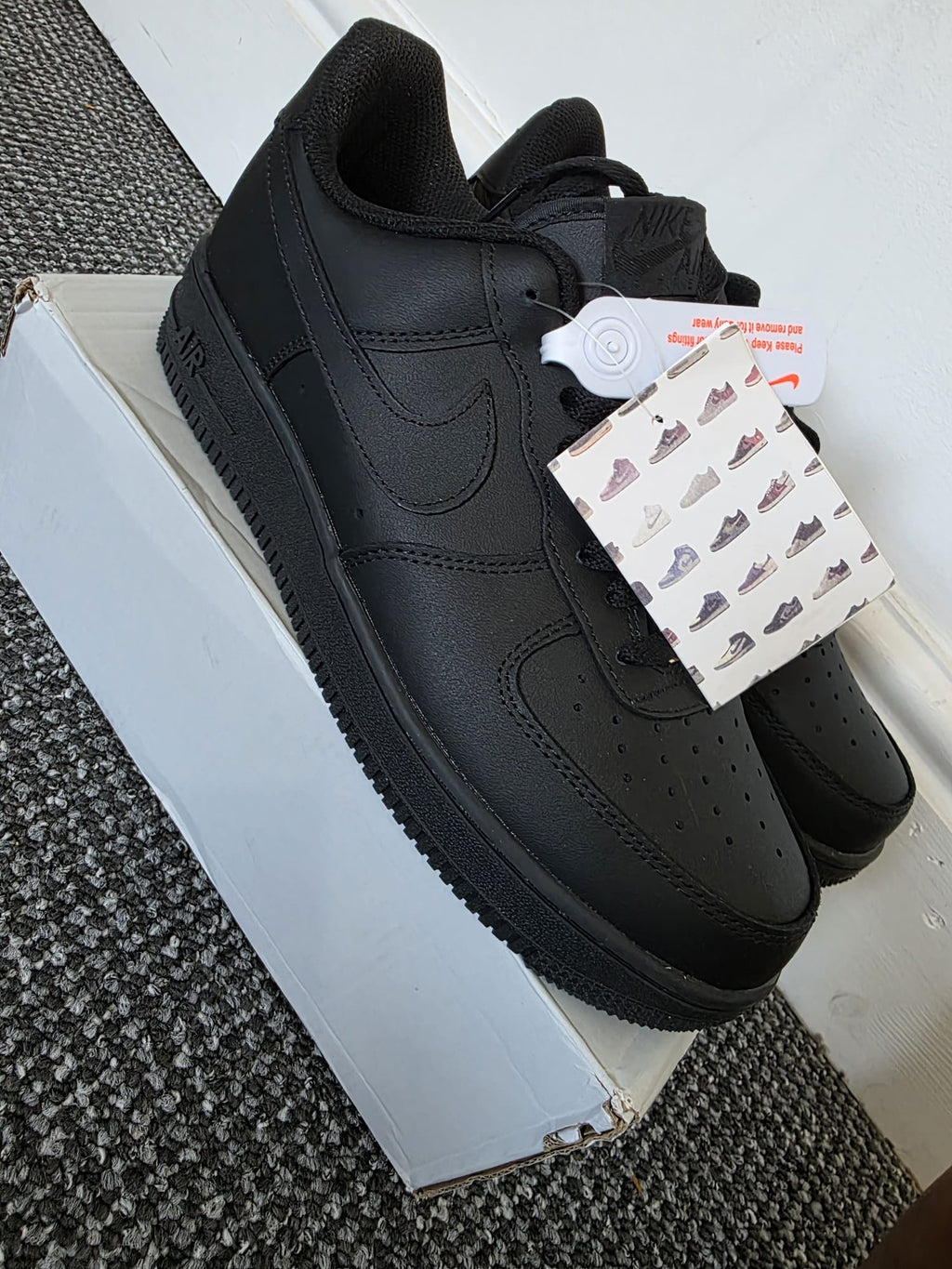 Triple-black Nike Air Force 1 Lows on display with matte black leather and matching details.