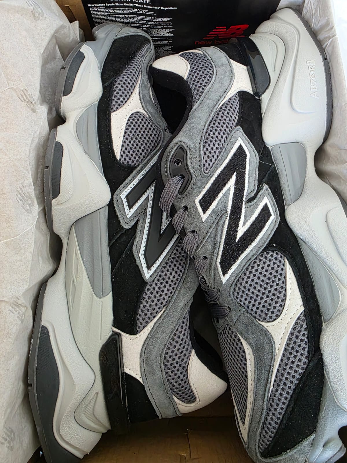New Balance 9060s - stylish sneakers in a box featuring a blend of grey and black design elements.